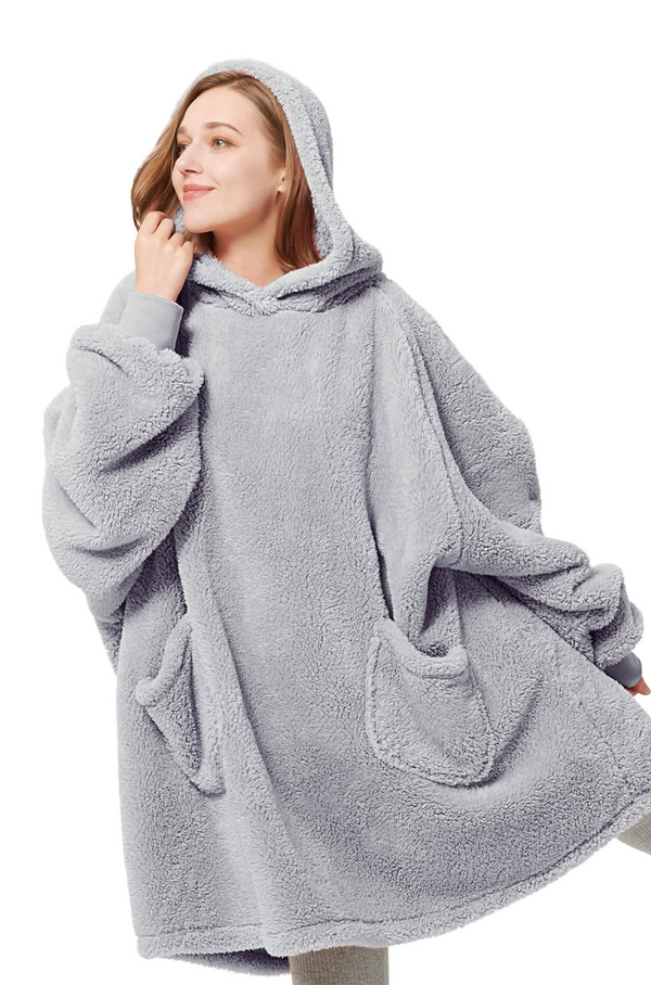 Person wearing a gray fleece poncho with hood on a white background
