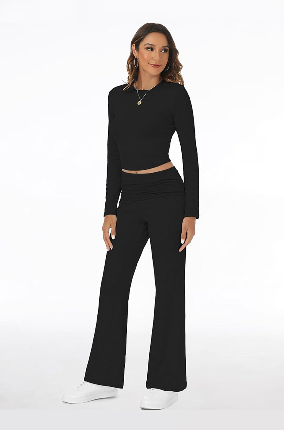Woman wearing a black long-sleeve top and black flared pants on a white background
