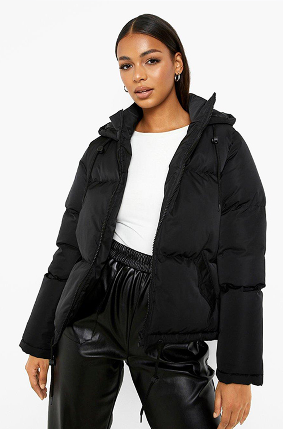 Woman wearing a black puffer jacket and black pants on a white background