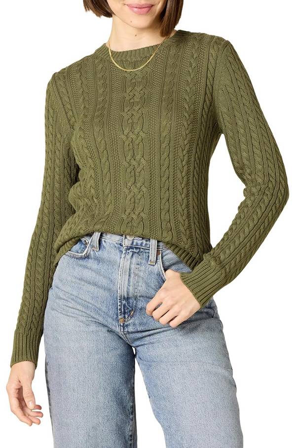 Person wearing a green cable knit sweater and blue jeans on a white background