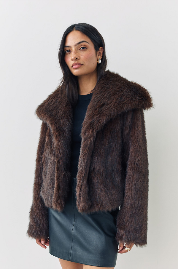 Woman wearing a brown fur coat against a white background